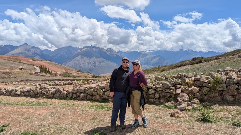 Leigh and Tom standing in front of mountains and dramatic clouds